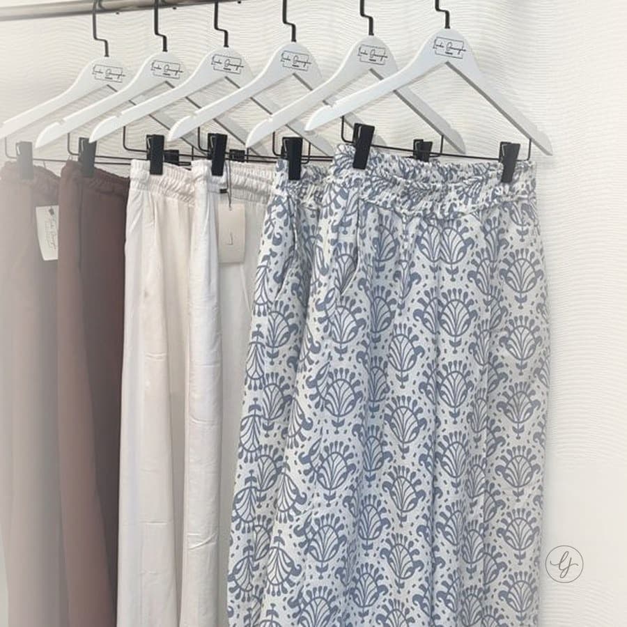 Wide-leg trousers in burgundy, white, and patterned blue on hangers